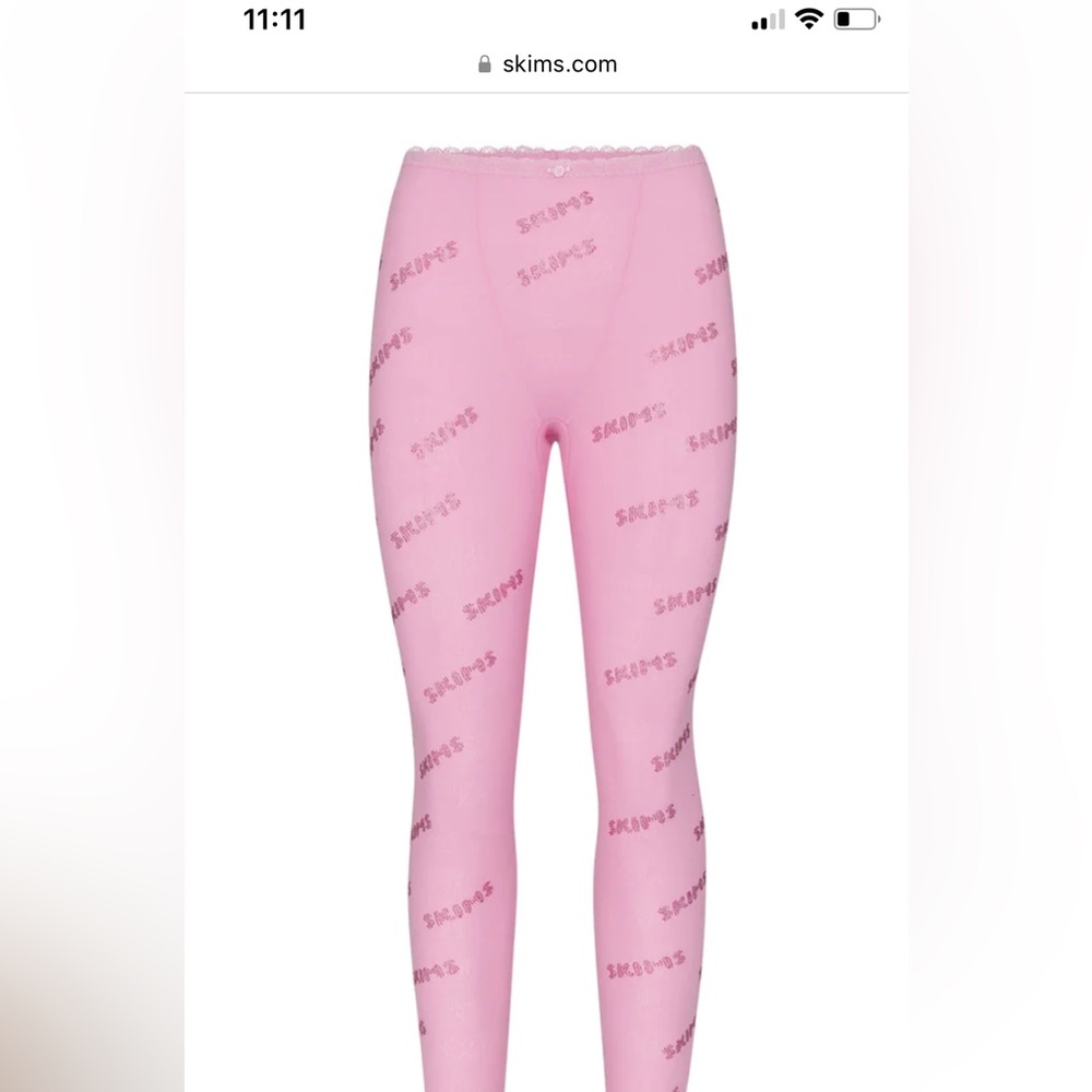Skims pink leggings with diamond writing on them